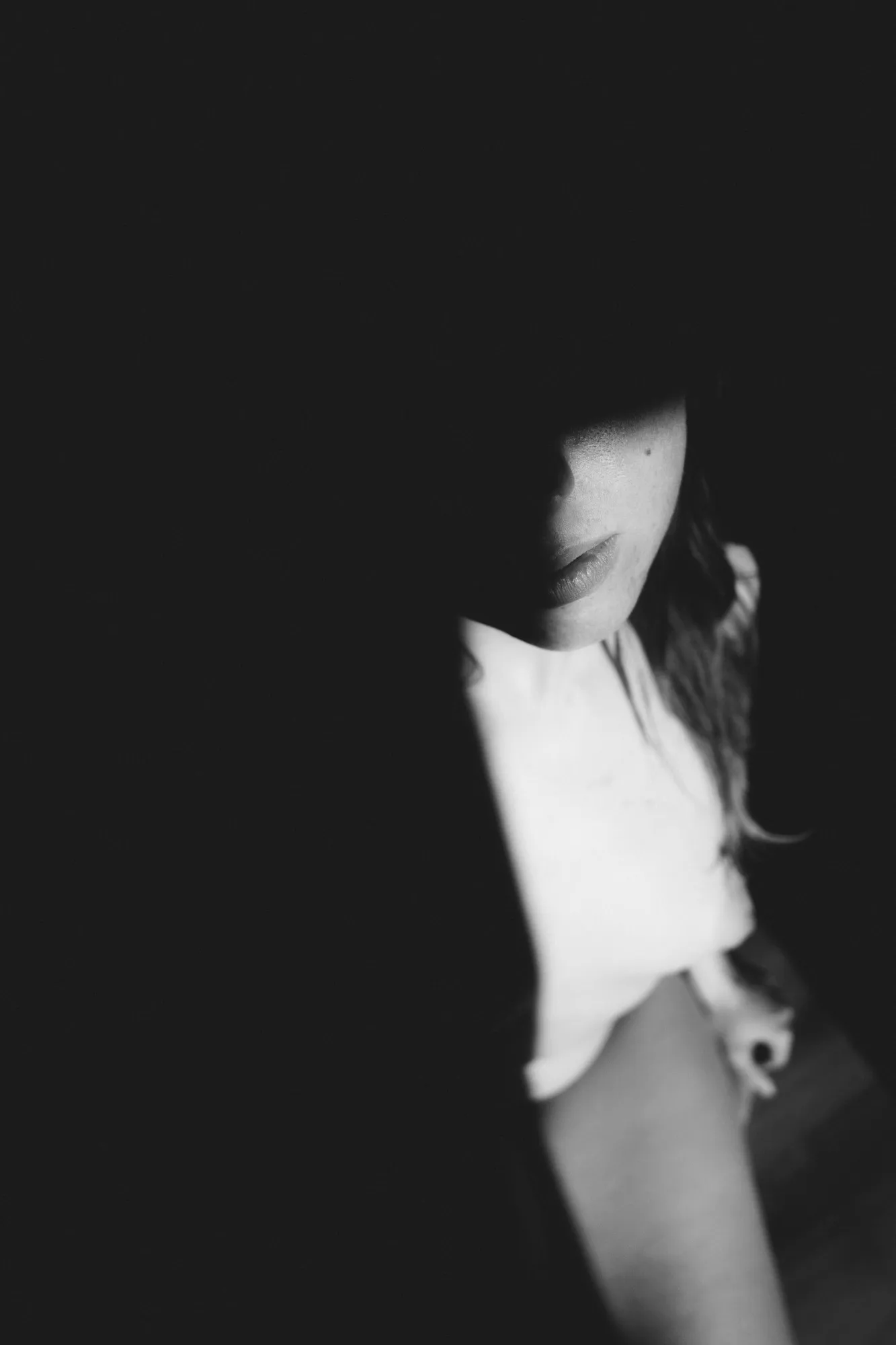 Untere Gesichtshälfte und Schulter einer Frau im Licht, der Rest im Dunkeln